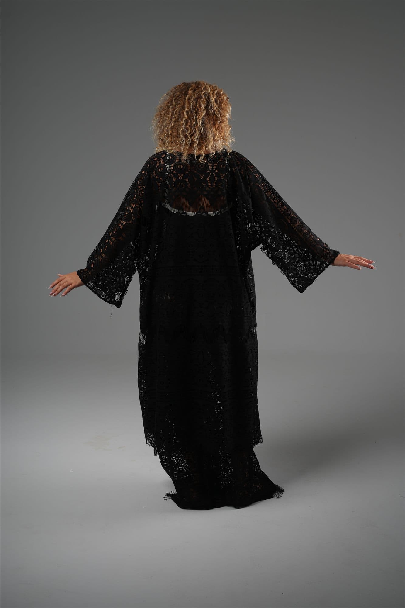 Model in the black Mashrabiya lace kimono, arms open, seen from behind