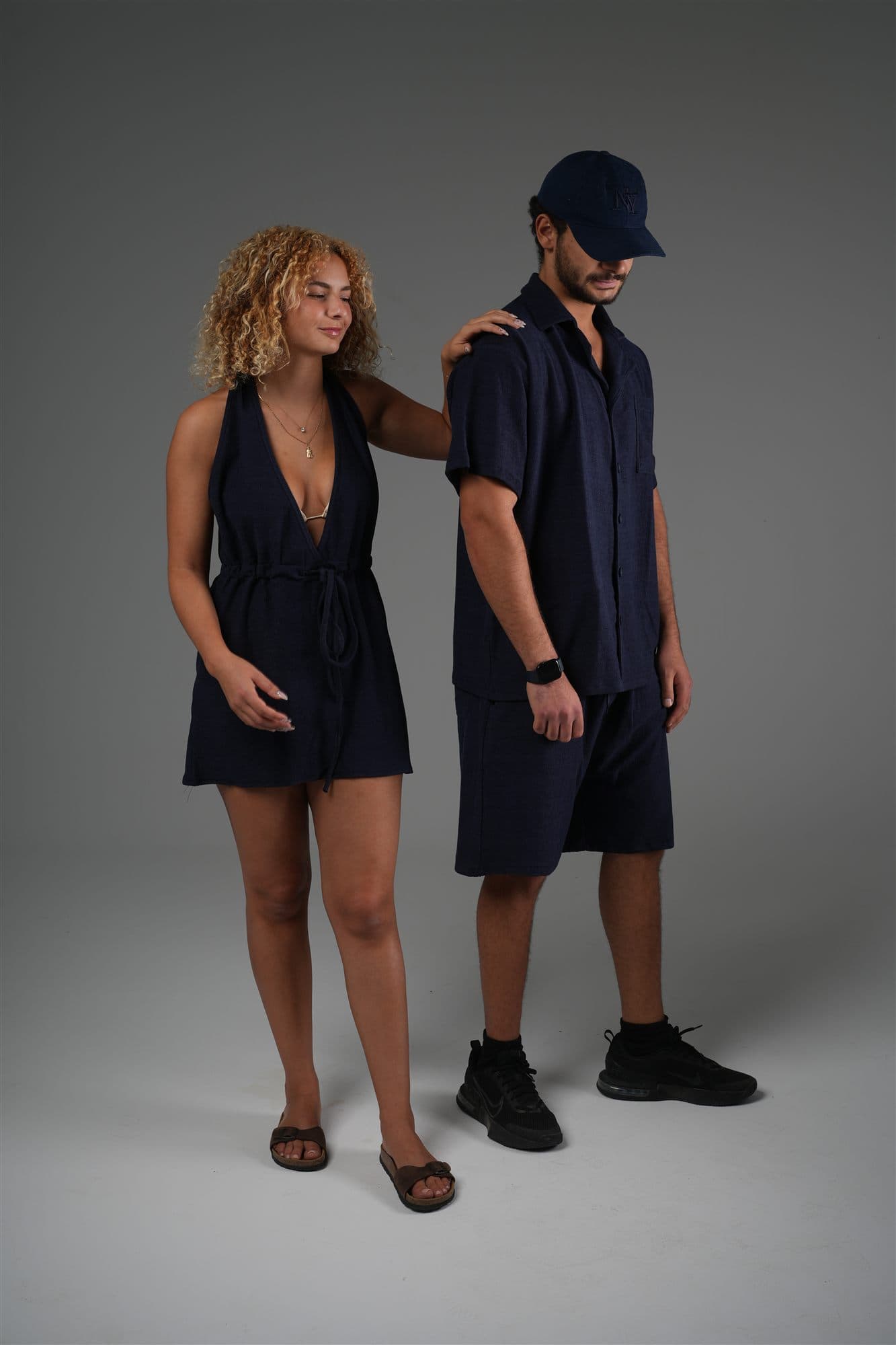 Two models in navy Riva terry: a halter wrap top, and a camp shirt with shorts
